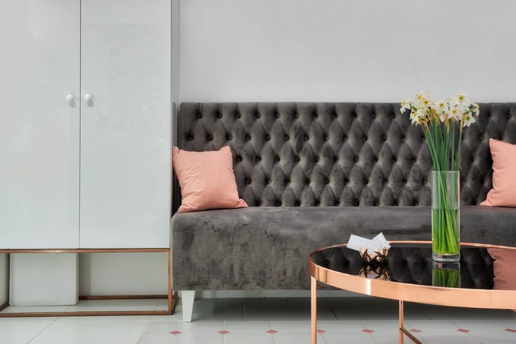 Grey couch with pink cushions and glass coffee table